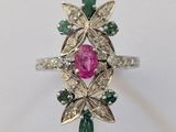 un gros plan d'une bague ornée d'une pierre rose entourée de pierres vertes et blanches
