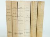 several old books sitting on top of each other on a white surface