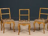 pair of gilded chairs with floral upholstered seat cushions