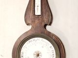 une horloge en bois accrochée au mur, sur laquelle se trouve un baromètre