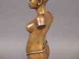 statue of a woman with a large breast on a wooden base