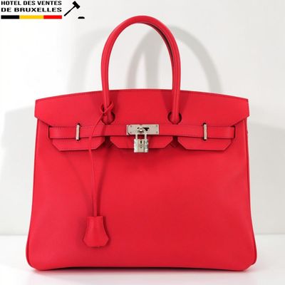 un sac à main en cuir rouge muni d'un cadenas sur la poignée