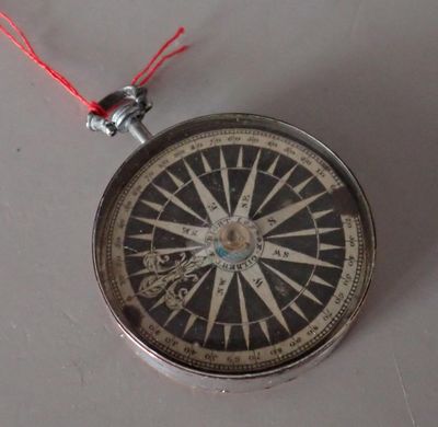 a compass with a red string hanging from it