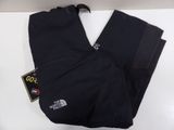 un gros plan sur un pantalon noir posé sur une surface blanche
