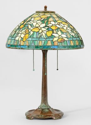 une lampe dont l'abat-jour en vitrail repose sur un socle en bois