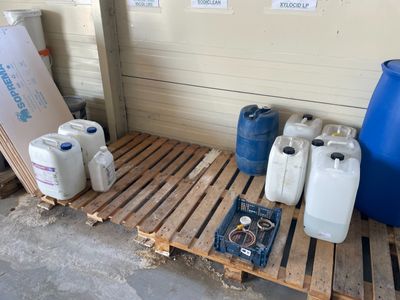 plusieurs récipients remplis d'eau posés sur une palette à côté d'un fût bleu