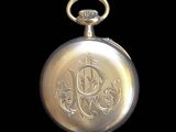 an image of a gold pocket watch with a monogram on it