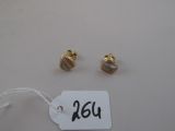 une paire de boucles d'oreilles plaquées or et une étiquette posée sur une table blanche