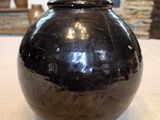 un vase noir posé sur une table devant une cheminée