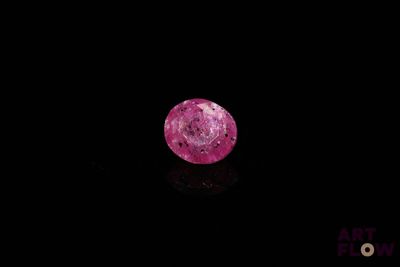 a close up of a pink diamond on a black surface
