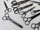 many pairs of scissors sitting on a white surface