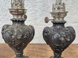 pair of antique oil lamps on wooden table with white wall in background
