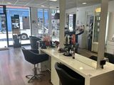 une photo d'un salon de coiffure avec de nombreux fauteuils