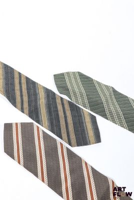 trois cravates sont disposées sur une surface blanche, sur fond blanc