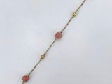 un bracelet plaqué or avec des perles roses et une chaîne en or