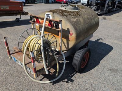 un petit chariot muni d'un tuyau, garé sur un parking