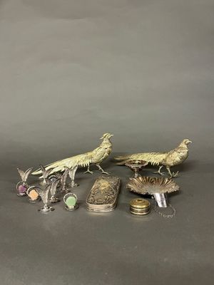 deux oiseaux en argent et d'autres objets en argent sur un fond gris