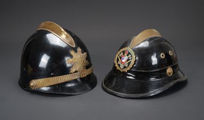 deux casques noirs ornés de galons dorés sur fond gris