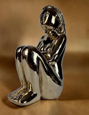 statue en argent représentant une femme assise à genoux sur un fond marron