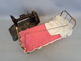 un petit lit de poupée avec une couverture rose et une machine à coudre