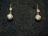 une paire de boucles d'oreilles en or et diamants sur une surface noire