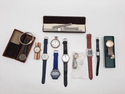 Plusieurs montres et autres objets sont disposés sur une surface blanche