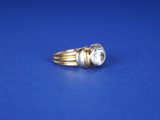 un gros plan d'une bague en or et diamants sur fond bleu