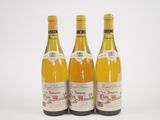 trois bouteilles de vin posées les unes à côté des autres sur une surface blanche