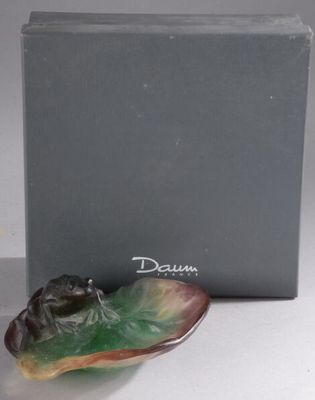 la figurine d'une grenouille est posée sur une feuille devant une boîte