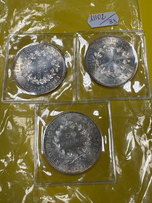 trois pièces d'argent dans des sachets en plastique posées sur une surface jaune