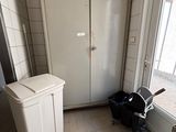 a trash can in the corner of a room next to a window