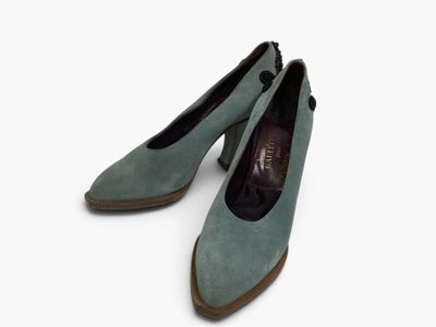 a pair of blue sued shoes on a white surface