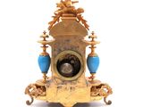 a gold clock with a blue vase on top of it