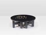 une table basse noire avec des pois dorés sur le plateau