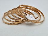 un gros plan sur une pile de bracelets en or posés sur une surface blanche