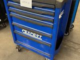 un gros plan sur une caisse à outils bleue à roulettes dans un garage