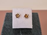 a pair of gold earrings sitting on top of a marble block