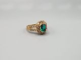 a close up of a gold ring with a green stone