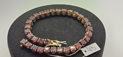 deux bracelets ornés de perles rouges et dorées, présentés dans un présentoir noir