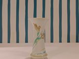 a white vase sitting on a table with a blue and white striped wall behind it