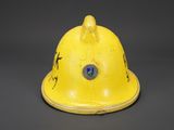 an old yellow fireman ' s helmet on a black background
