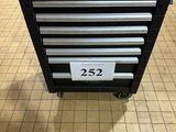 un gros plan d'une boîte à outils noire sur roulettes posée sur un sol carrelé