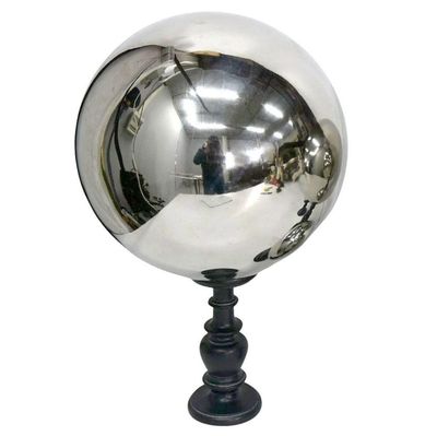 une boule argentée posée sur un socle noir, sur un fond blanc