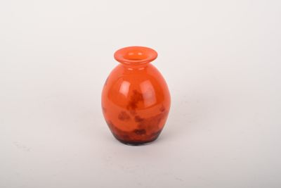 un petit vase en verre orange posé sur une surface blanche