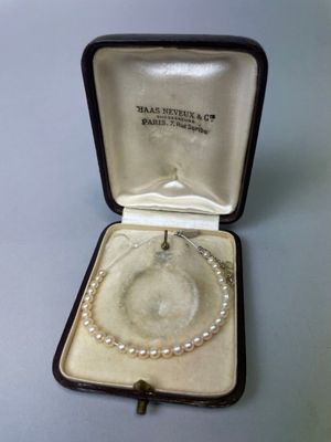 une photo d'un bracelet de perles dans un écrin orné d'une croix