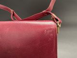 red leather shoulder bag on grey background with gold hardware