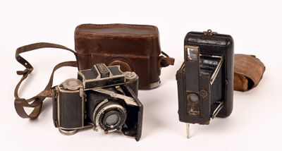 two old cameras sitting next to each other on a white surface