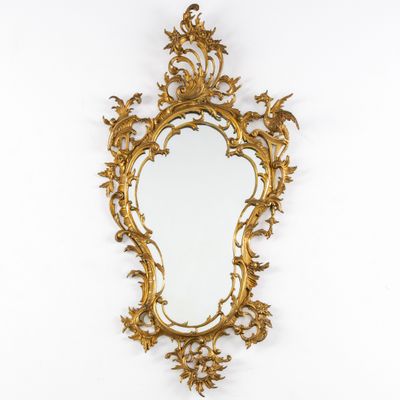 un miroir à dorures accroché au mur, à côté d'un mur blanc