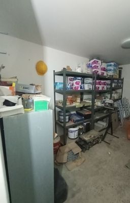 une photo d'une pièce dans laquelle se trouvent un réfrigérateur et des étagères