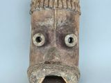 une image représentant un masque en bois avec des yeux et des dents